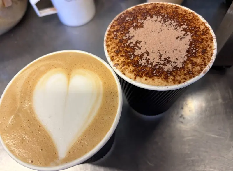 Coffee with heart latte art beside a hot chocolate