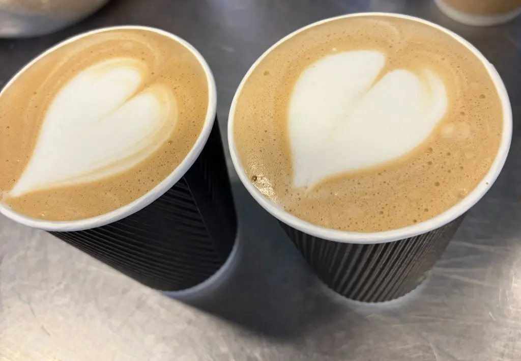 Two takeaway coffees with heart latte art from Upside Down Coffee on the Go
